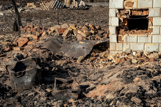 Casas destruídas como resultado de um incêndio na Rússia Tijolos e partes de paredes vários utensílios domésticos janelas quebradas cobertas de cinzas na superfície da terra Desastre natural