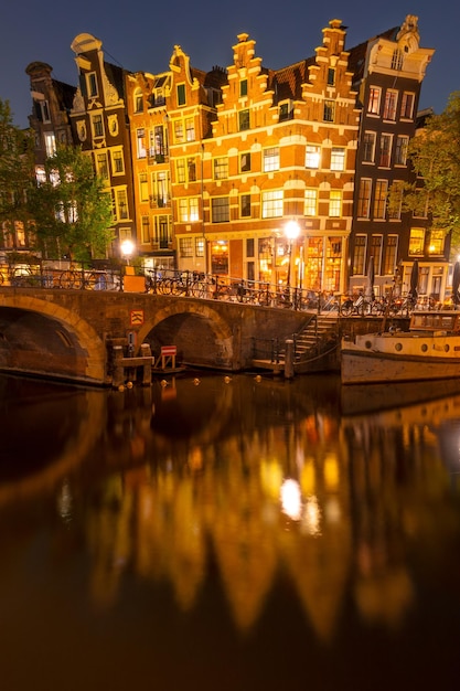 Casas holandesas danzantes en el canal de Ámsterdam por la noche
