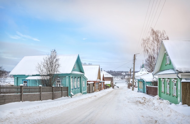 Casas de madera en la calle Nikolskaya y una vista del Volga congelado en Plyos a la luz de un día de invierno bajo un cielo azul