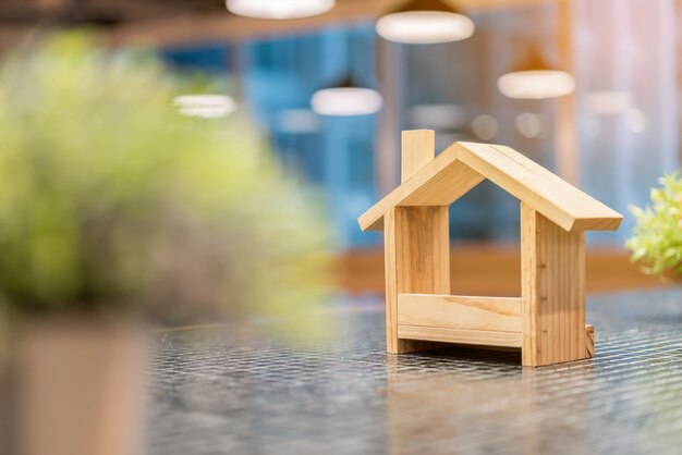 Casas de madera en miniatura y plantas verdes borrosas en primer plano.