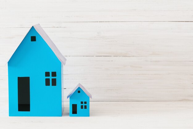 Casas de papel azul en mesa de madera blanca