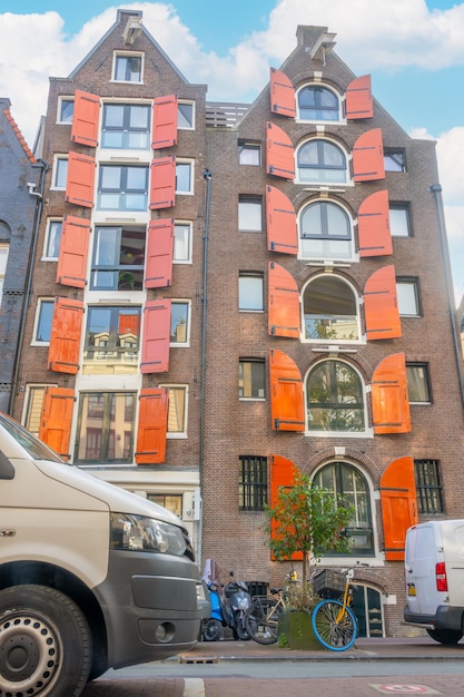 Casas con persianas rojas en Ámsterdam y coches y bicicletas