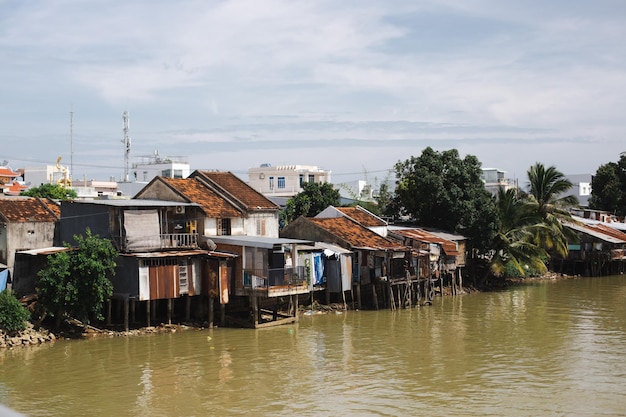 Casas pobres y viejas en el agua cerca de un río sucio en Asia Vietnam contra el telón de fondo de una montaña en un día soleado