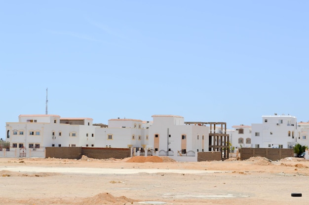 Foto casas retangulares árabes brancas no deserto com janelas contra o fundo amarelo