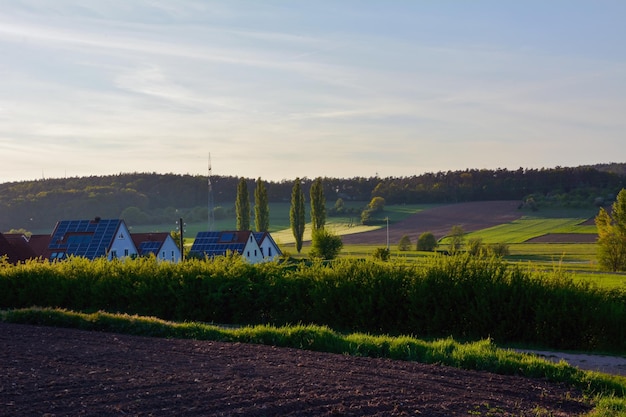 Casas rurales con paneles solares en los techos En primer plano hay un campo agrícola arado