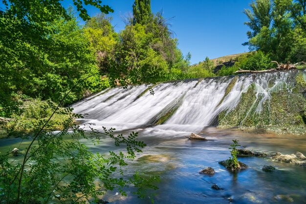 Cascada de agua deslizándose por la pared de piedra en el bosque de plantas verdes. Duratón, Sepúlveda, Segovia,