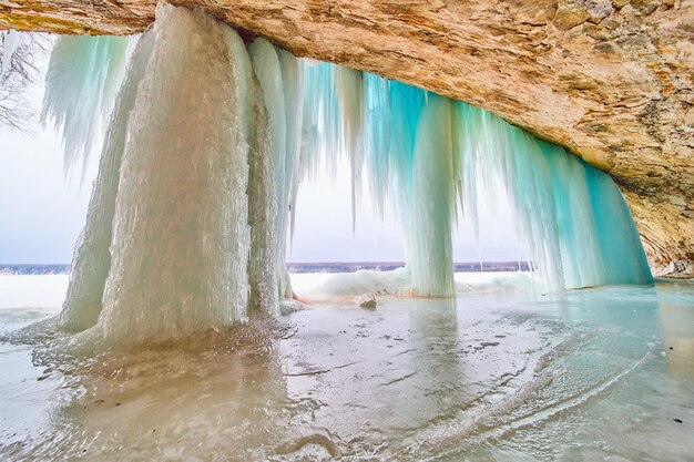 Cascada congelada en el lago dentro de la cueva que se abre con carámbanos azules