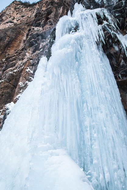 Foto cascada congelada en la montaña rocosa en día de invierno