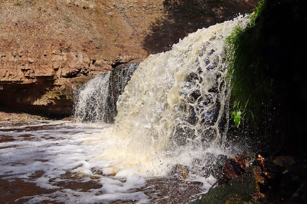 Cascada de corriente de agua cayendo sobre las rocas de cerca