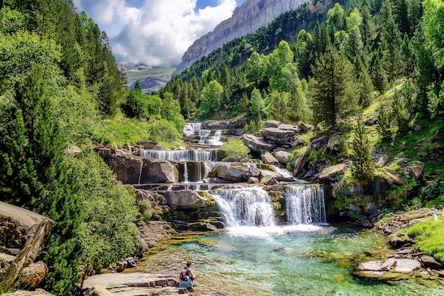 Cascada en escalinatas o terrazas en verde paisaje entre árboles y montañas en Ordesa. Soaso se pone de pie.