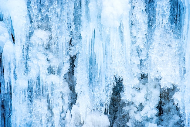 Cascada de hielo congelado de carámbanos azules en la roca