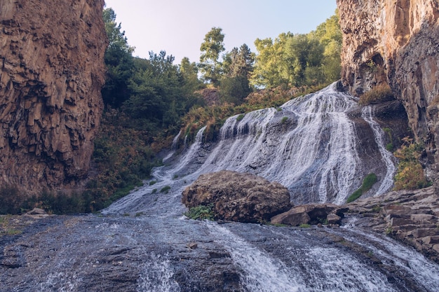 Cascada de Jermuk, corriente que fluye, vista pintoresca entre las rocas del cañón, desfiladero iluminado por el sol, armenio foto de archivo