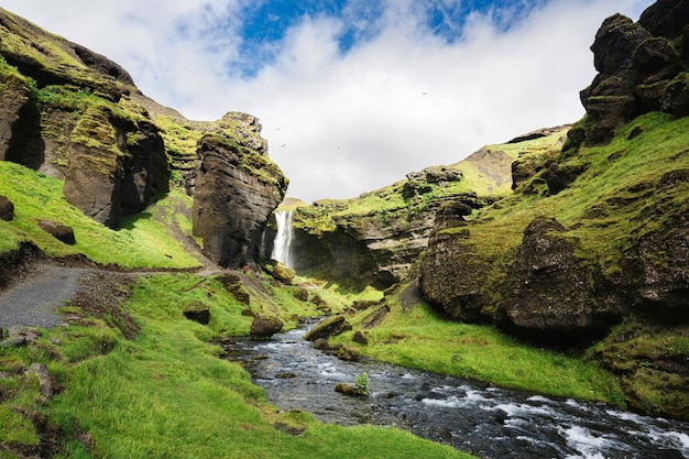 Cascada de Kvernufoss que fluye a través del valle verde en un día soleado en verano en Islandia