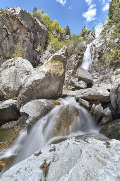 Una cascada en las montañas con un cielo azul detrás