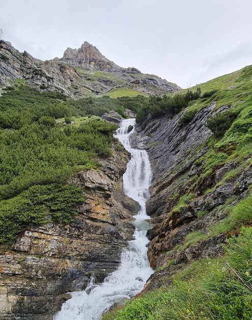 Una cascada en las montañas con una montaña al fondo