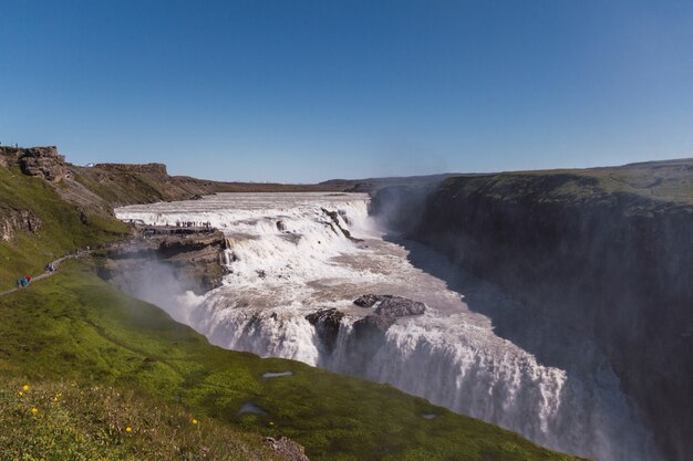 Cascada muy alta y hermosa en Islandia. Cascada de ensueño en los verdes valles de la hermosa isla de Islandia