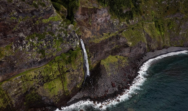 Cascada rápida que atraviesa la montaña rocosa en el mar ondulado