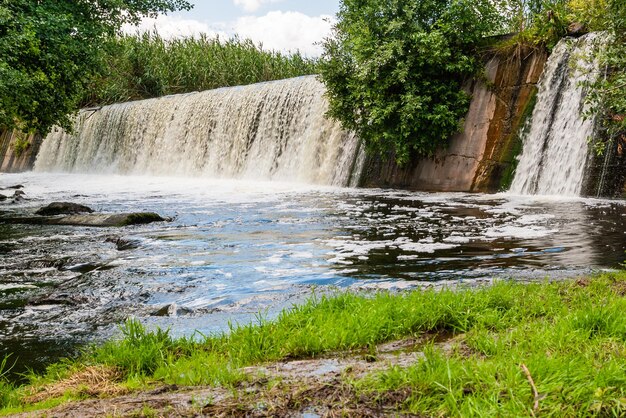 Cascada sobre un fondo de hierba verde y cielo azul