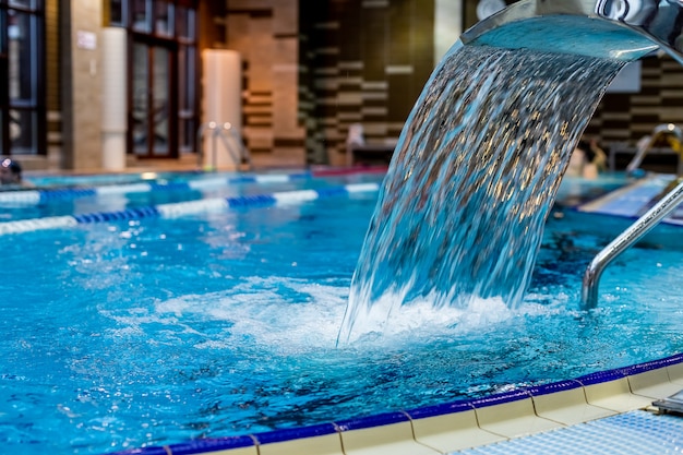 Una cascada turquesa, masaje de espalda y hombros en la piscina.