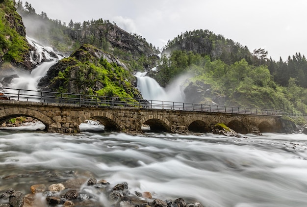 Las cascadas gemelas de Latefoss fluyen bajo los arcos del puente de piedra del condado de Hordaland Odda Noruega