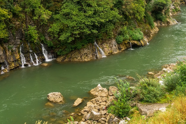 Cascadas en un río de montaña con agua verde y costas rocosas