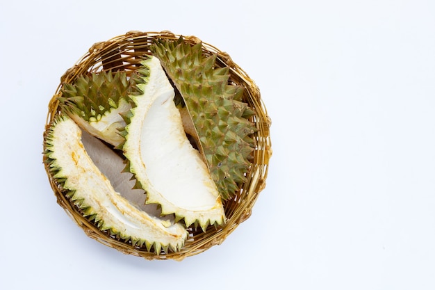 Cáscara de durian en cesta de bambú sobre fondo blanco.