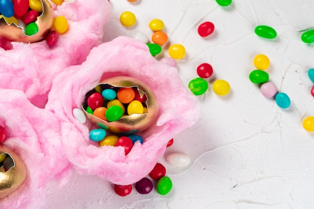 Cáscara de huevo con caramelos de colores dentro de un nido decorativo de Pascua