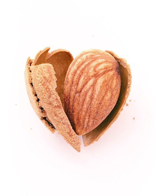 Cáscara de nuez de almendras de cerca agrietada en forma de corazón aislada sobre fondo blanco. Me encanta el concepto de alimentación saludable.