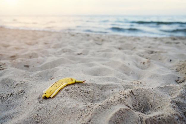 Cáscara de plátano tirada en la playa de arena contaminación de la playa