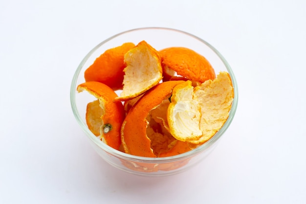 Cascas de laranja em uma tigela de vidro na superfície branca