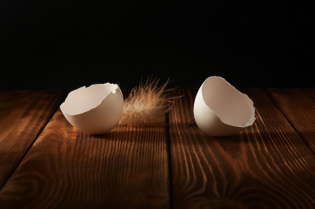 Cascas de ovo de um ovo de galinha quebrado em uma mesa de madeira em um escuro.