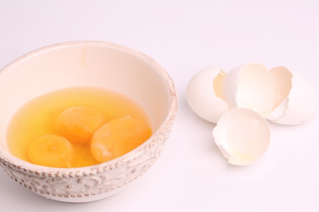 Cascas de ovos quebradas em uma tigela em um foco suave seletiva de fundo branco