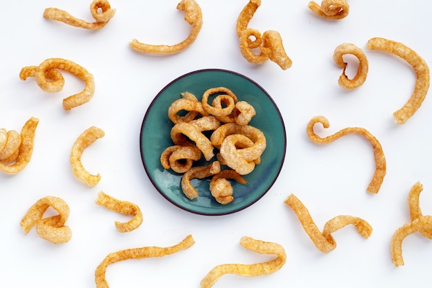 Cascas de porco fritas crocantes em fundo branco.