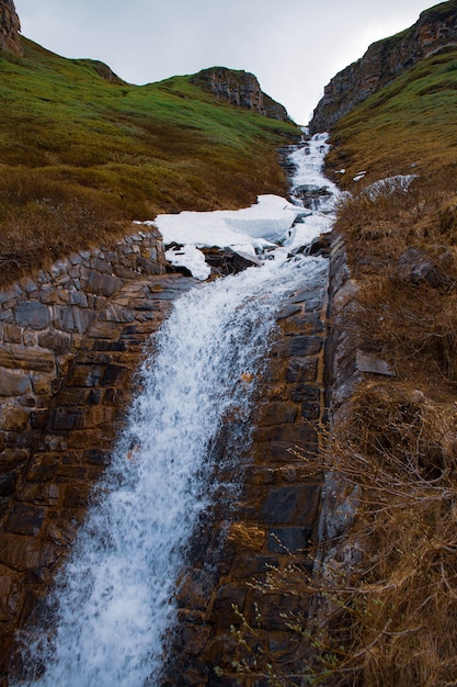 Foto cascata caindo sobre rochas cobertas de musgo