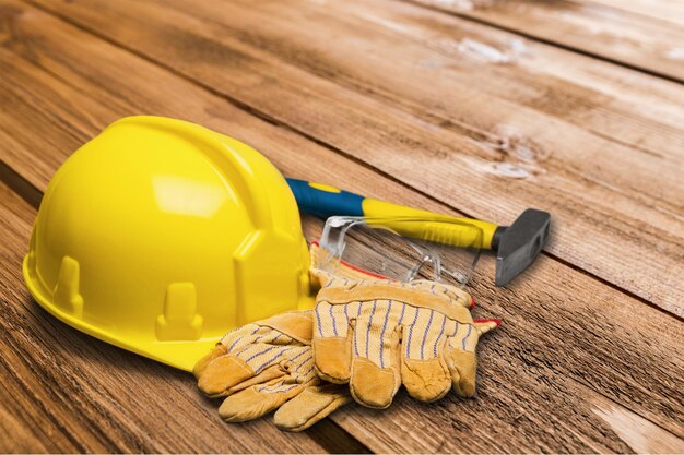 Casco amarillo y guantes de trabajo de cuero, martillo