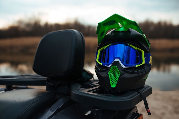 Un casco ATV verde resistente al fondo el río y la arena. deporte y concepto extremo.