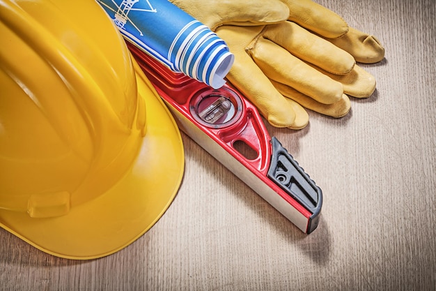 Casco de construcción guantes de protección nivel de construcción azul dibujos de ingeniería enrollados en tablero de madera