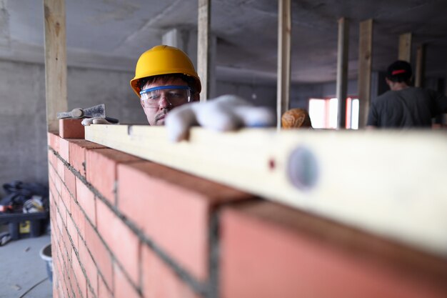 Foto el casco de construcción mide el nivel de ladrillo
