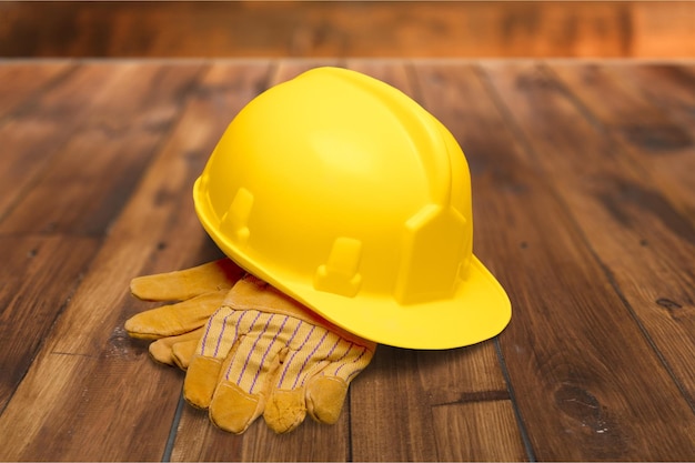 Casco y guantes amarillos en la mesa de madera