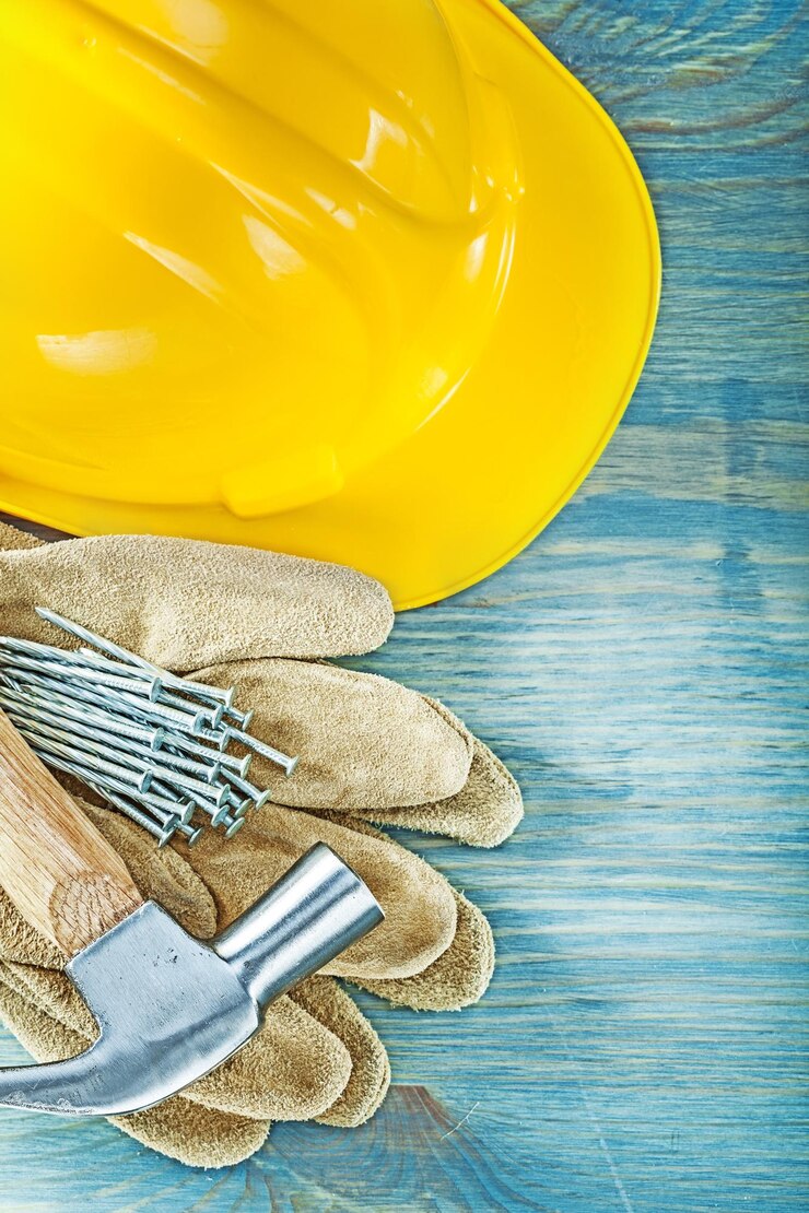 Foto casco, guantes de seguridad de cuero, clavos de martillo en el concepto de construcción de tableros de madera