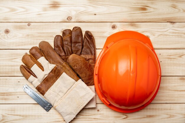 Casco y guantes de trabajador de la construcción en la vista superior de la superficie de madera