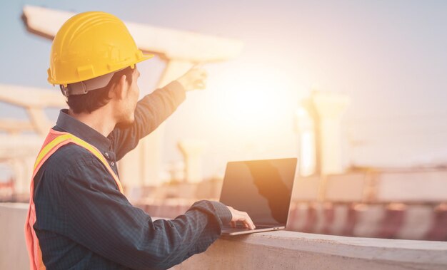 Casco de ingeniero de primer plano usando computadora portátil para trabajar en el sitio de construcción