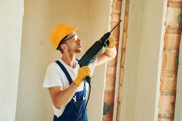 En casco joven trabajando en uniforme en la construcción durante el día