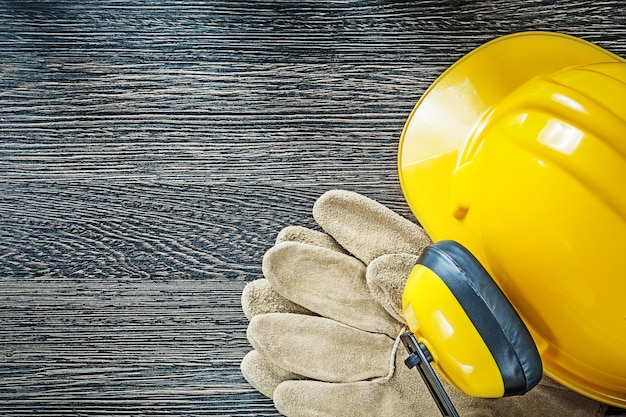 Foto casco orejeras guantes protectores de cuero sobre tabla de madera