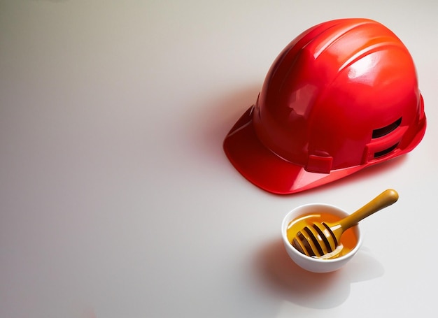 Casco rojo de construcción con tazón de miel.