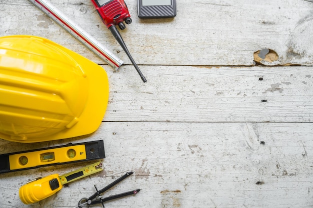 casco de seguridad amarillo y planos arquitectónicos enrollados en un escritorio de madera