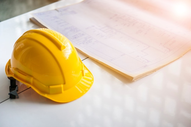 El casco de seguridad y el plano en la mesa en el sitio de construcción