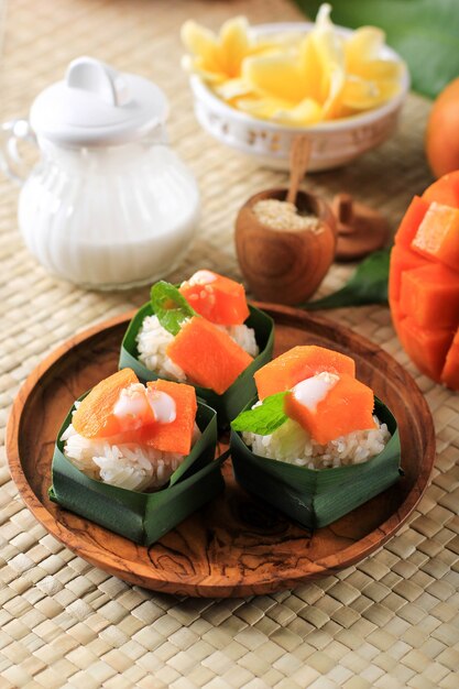 Caseira tropical thai sobremesa manga arroz pegajoso na mini tigela de folha de pandan. servido com delicioso leite de coco e baunilha para barrar com semente de gergelim.