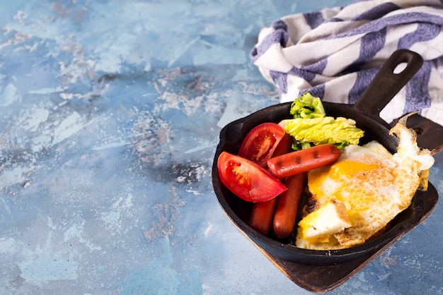 Caseiro delicioso café da manhã em uma panela com ovo frito, torradas, salsicha, legumes, café preto