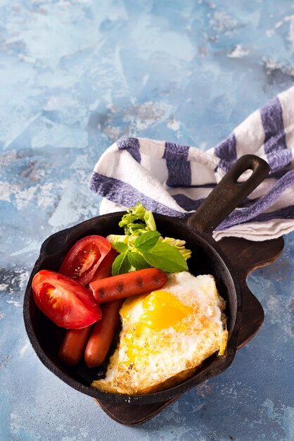 Caseiro delicioso café da manhã em uma panela com ovo frito, torradas, salsicha, legumes, café preto